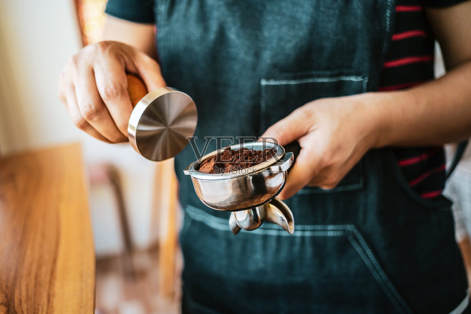 手工咖啡师制作咖啡用手工压碎咖啡用捣碎机在咖啡店，咖啡师拿着一个portfilter制作浓缩咖啡照片摄影图片