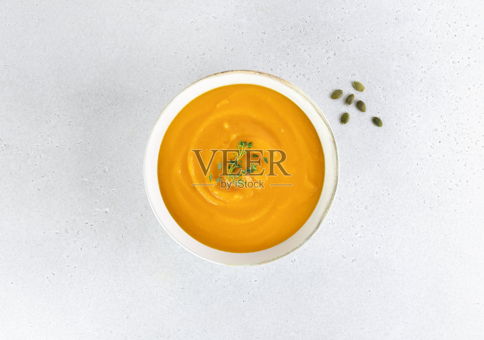 南瓜或胡萝卜汤，白色背景上有丝质的南瓜籽。前视图。照片摄影图片