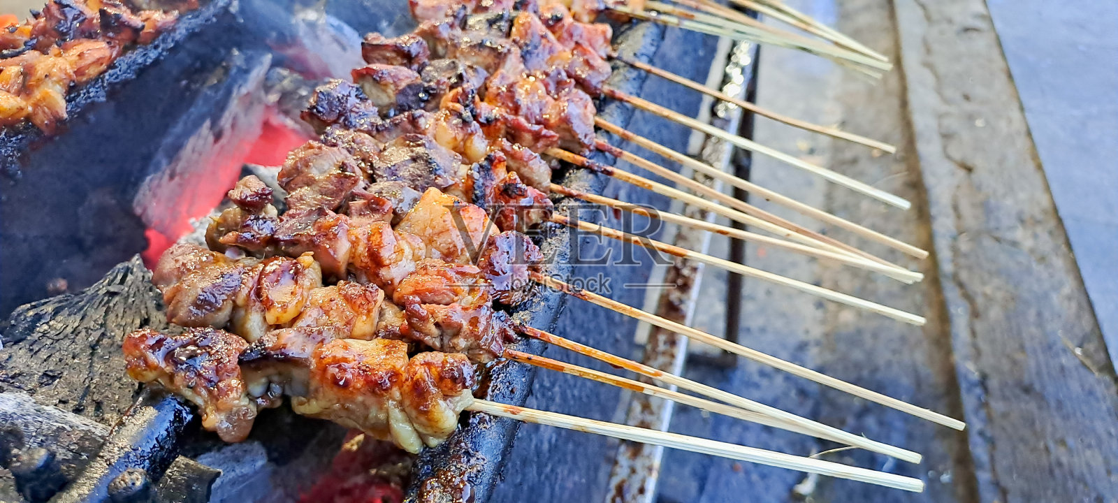 沙茶，山羊沙茶，羊肉，羊肉或肉山羊沙茶在烧烤的地方与烟雾的人与美味的样子。印尼爪哇的传统沙茶。照片摄影图片