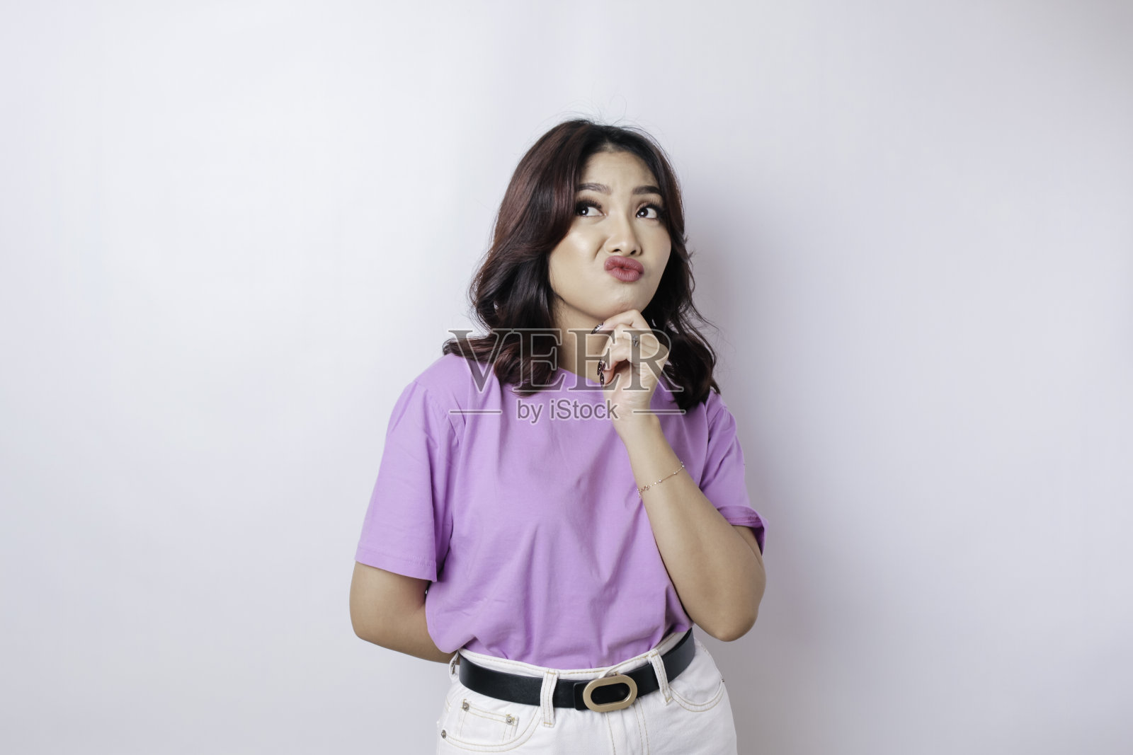 一个体贴的年轻休闲女孩的肖像，穿着淡紫色的衬衫，在白色的背景下孤立地看着一边照片摄影图片