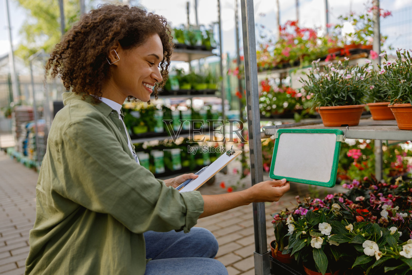 微笑的女花商拿着剪贴板在花卉中心进行盘点照片摄影图片