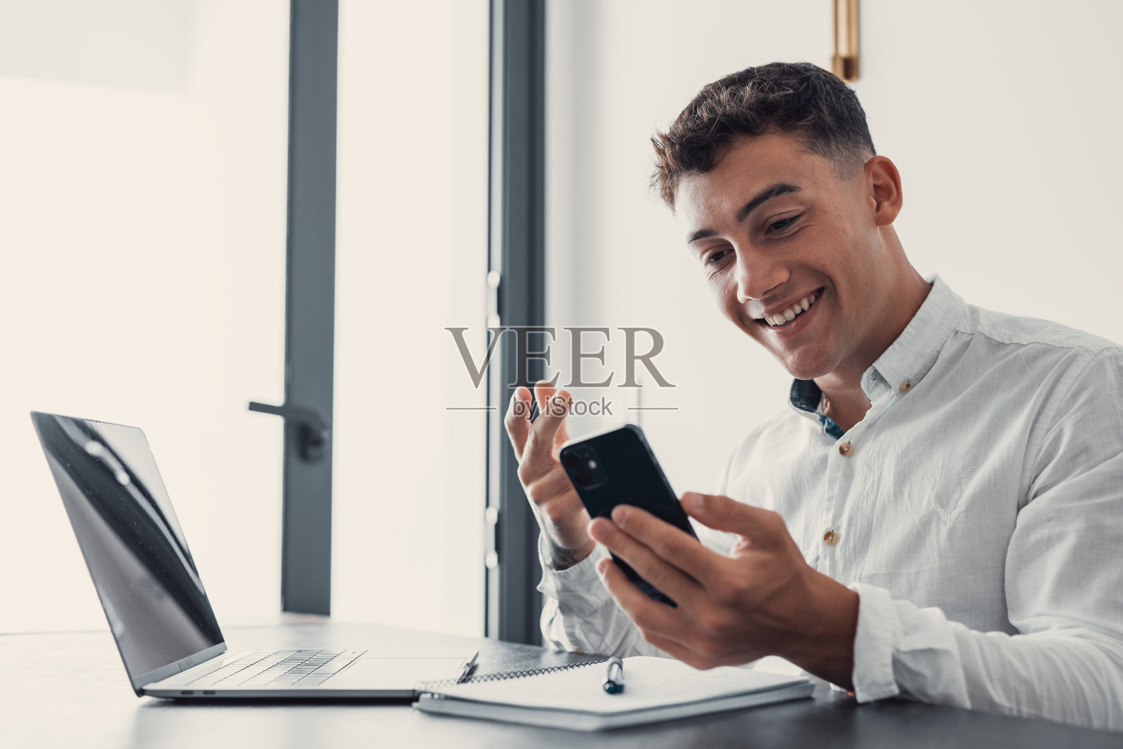 男人坐在办公桌前看笔记本电脑上的电子邮件，做出“是”的手势，感到高兴。男性企业家获得伟大的商业新闻，庆祝职业发展，进步。成就，胜利，瞬间竞拍胜利概念照片摄影图片