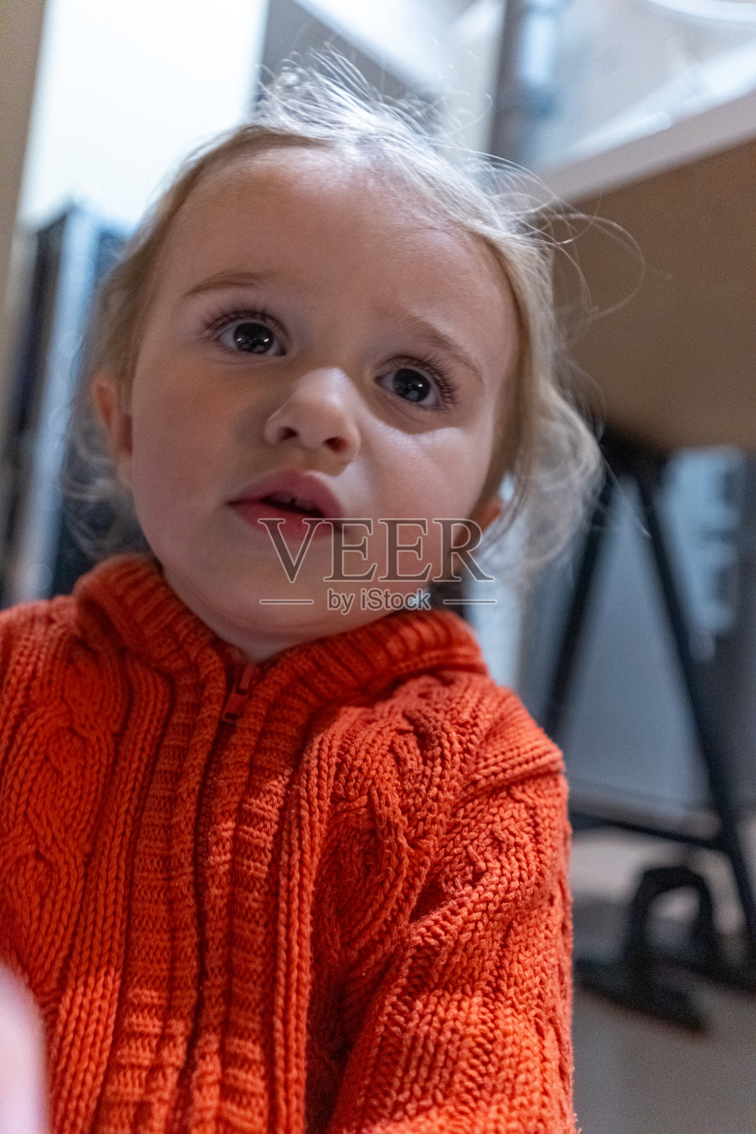 可爱的蹒跚学步的女孩穿着橙色的肖像。照片摄影图片