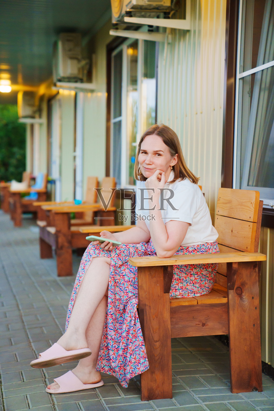 女人在露台上，在汽车旅馆房前的新鲜空气中放松。照片摄影图片