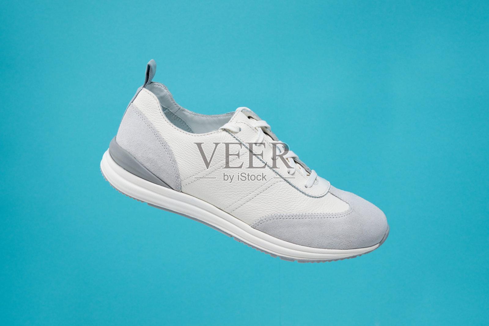 时尚白色运动鞋与皮革口音在柔和的渐变背景。运动鞋，街头穿在空中。产品照片或悬浮概念。照片摄影图片