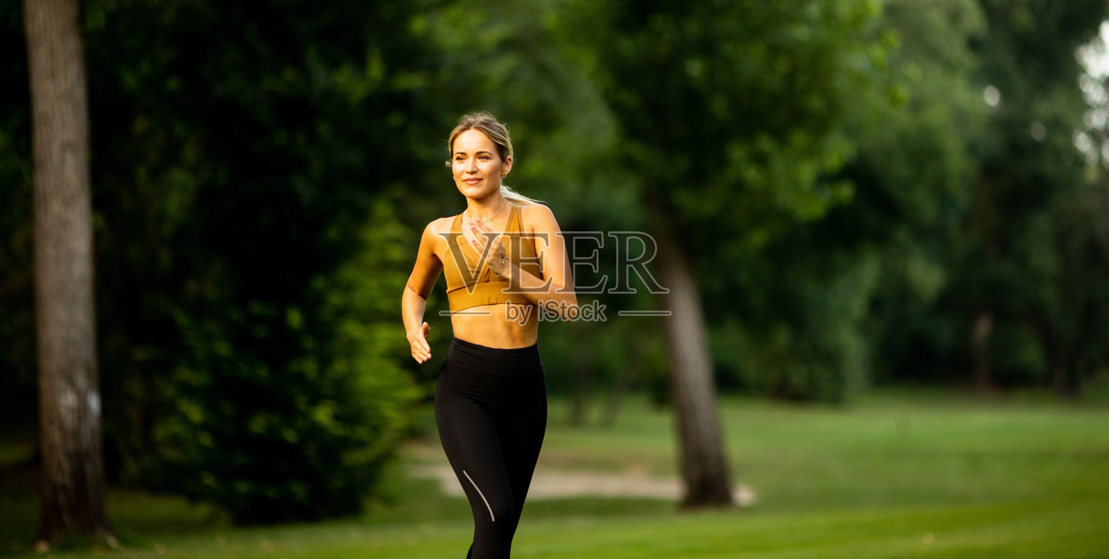 漂亮的年轻女子在公园里跑步照片摄影图片