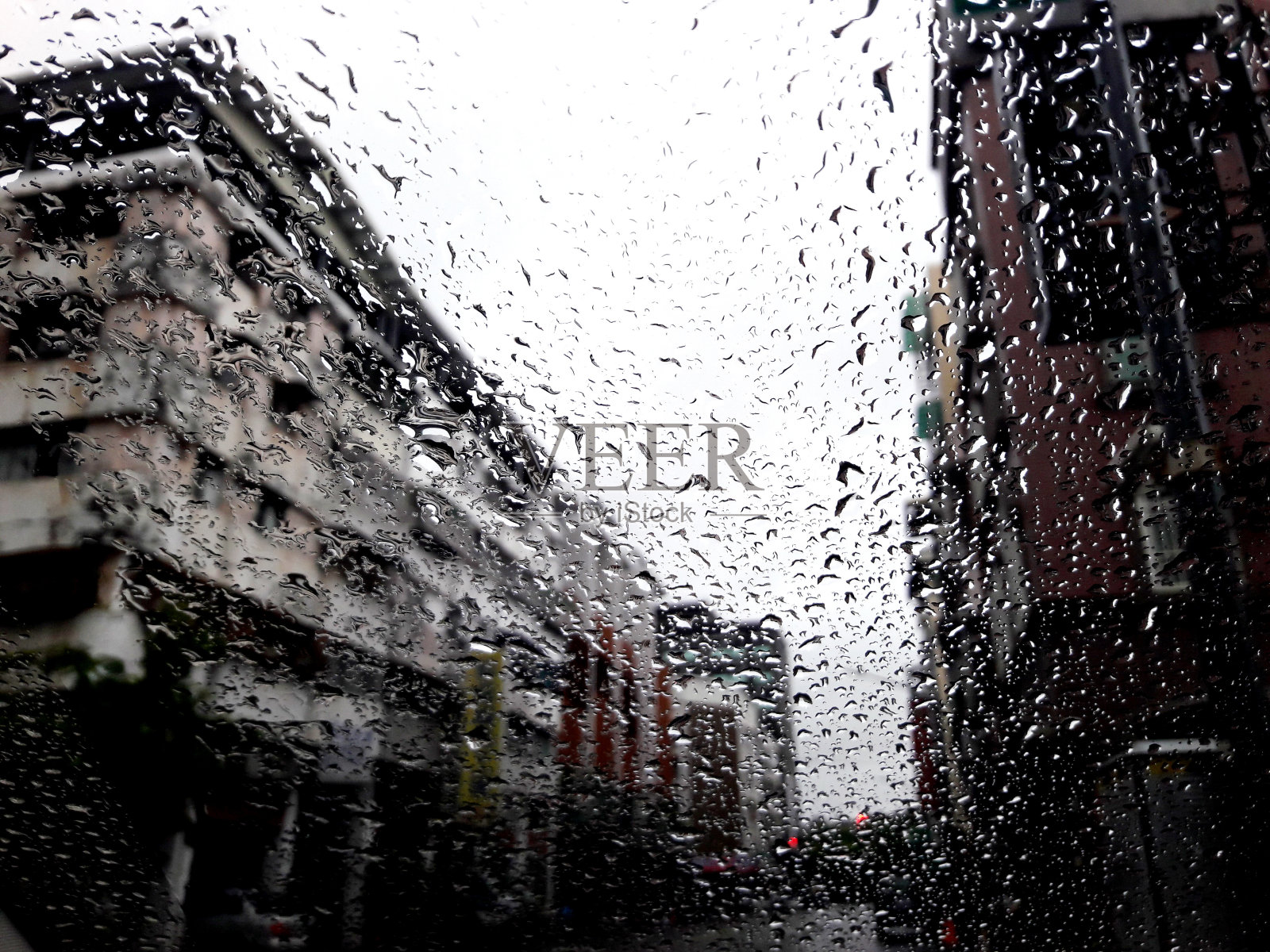 雨季大雨中雨滴落在湿透明窗玻璃上的特写，模糊的城市景观，雨中的倒影照片摄影图片