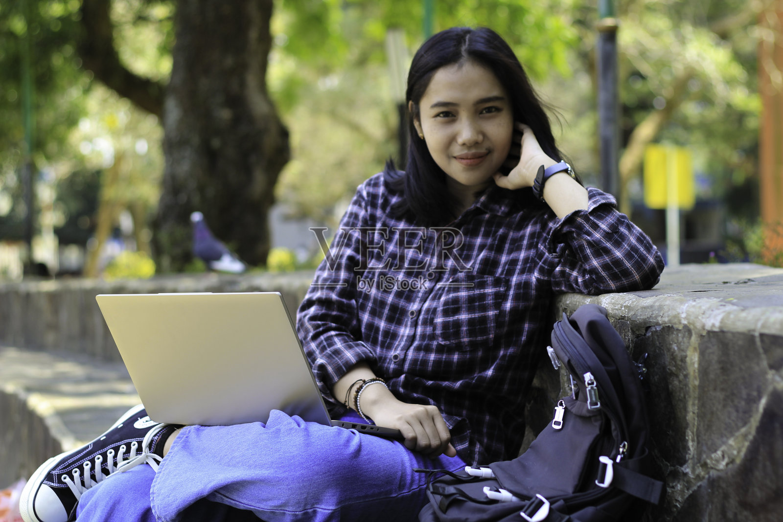 快乐的年轻亚洲女学生微笑着在笔记本电脑上做自由职业和家庭作业，看着相机照片摄影图片