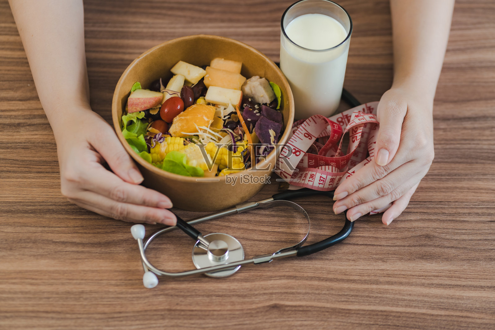 女性双手拥抱替代食物、蔬菜和水果。有一个卷尺和一个心脏监听器。健康食物概念照片摄影图片