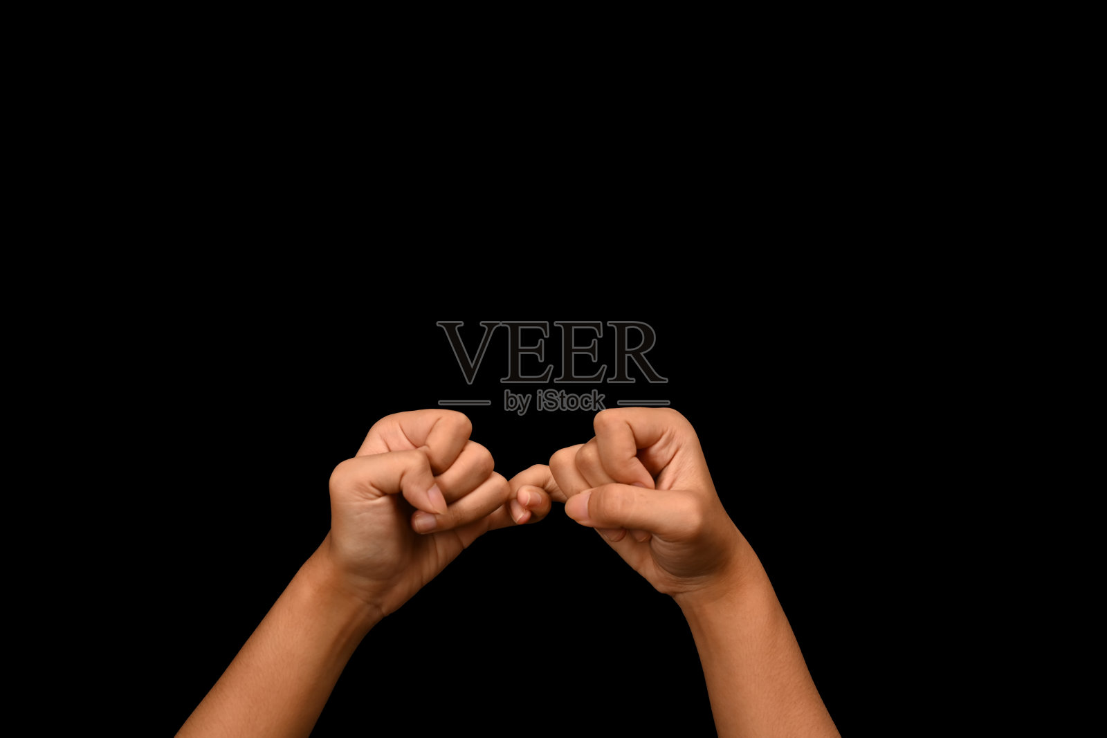 两只手互相钩住小指在黑色背景上，象征着承诺或原谅。照片摄影图片