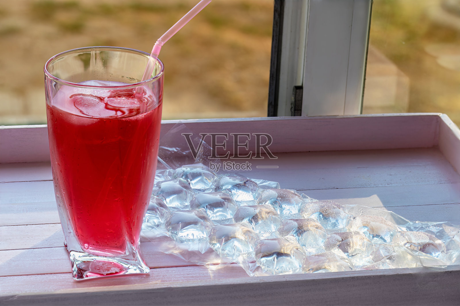 在加冰和吸管的玻璃杯中饮用。在一次性制冰袋旁边。饮料的冷却。照片摄影图片