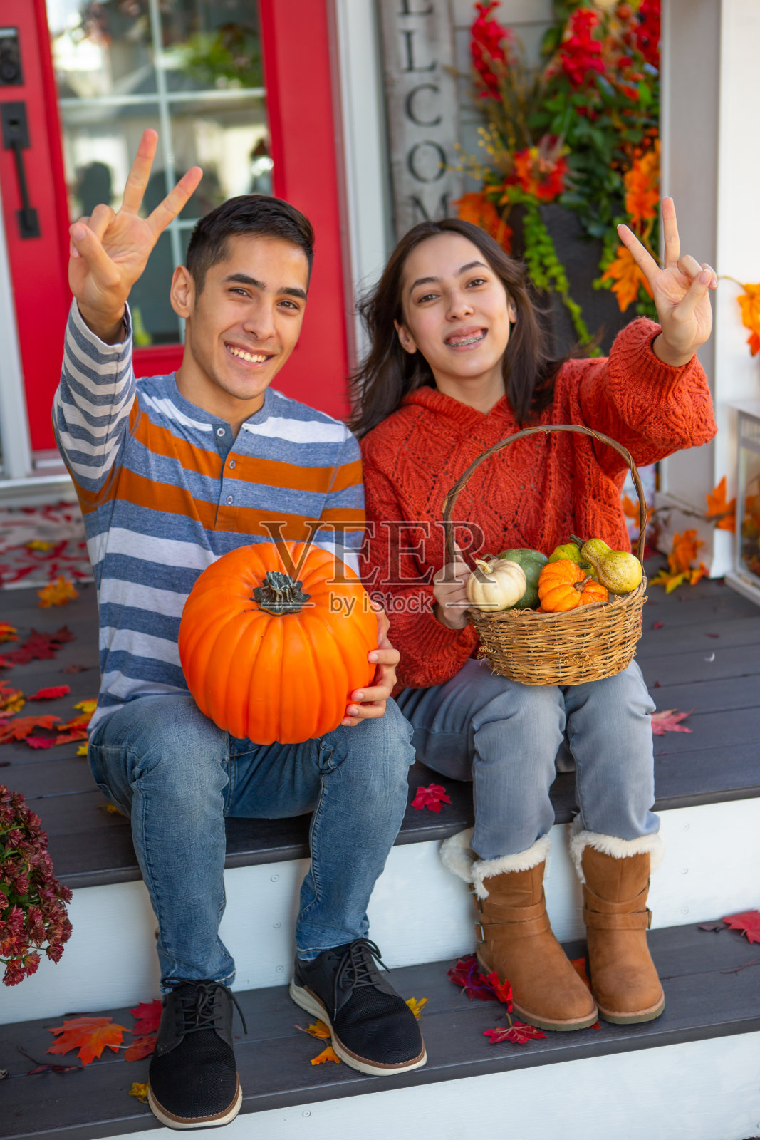 兴奋的兄弟姐妹坐在装饰的秋季门廊上照片摄影图片