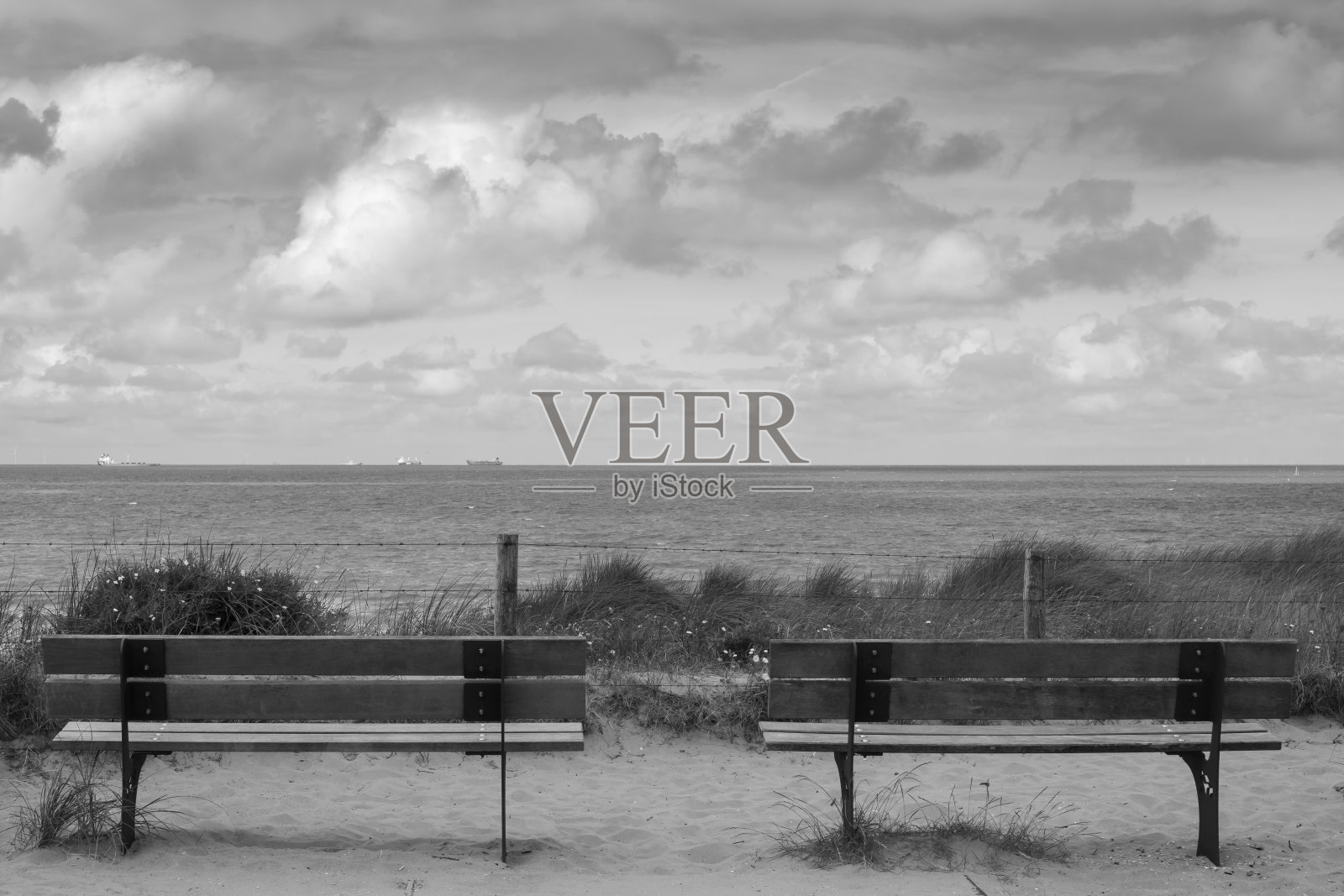 海岸上的两个木凳的静物画，背景是大海和戏剧性的天空。照片摄影图片