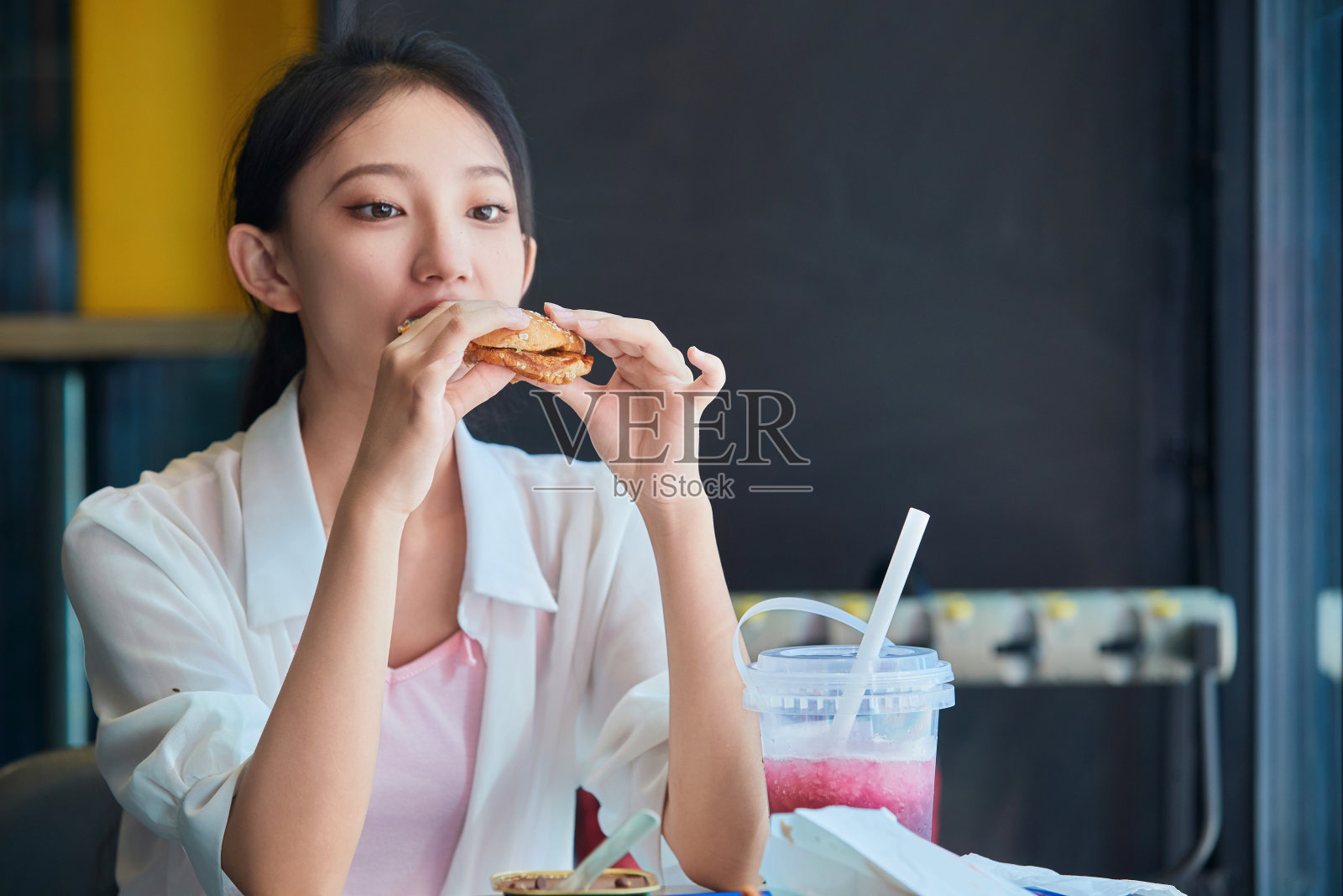一个可爱的十几岁的女孩在商场的快餐店吃饭照片摄影图片