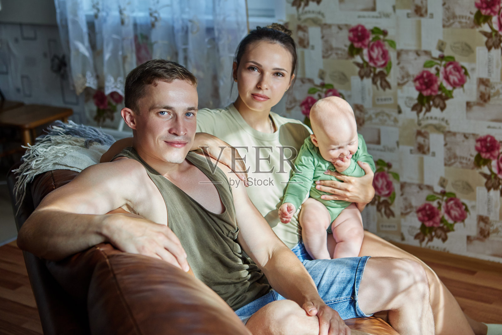 年轻夫妇带着孩子坐在客厅沙发上的全家福。照片摄影图片