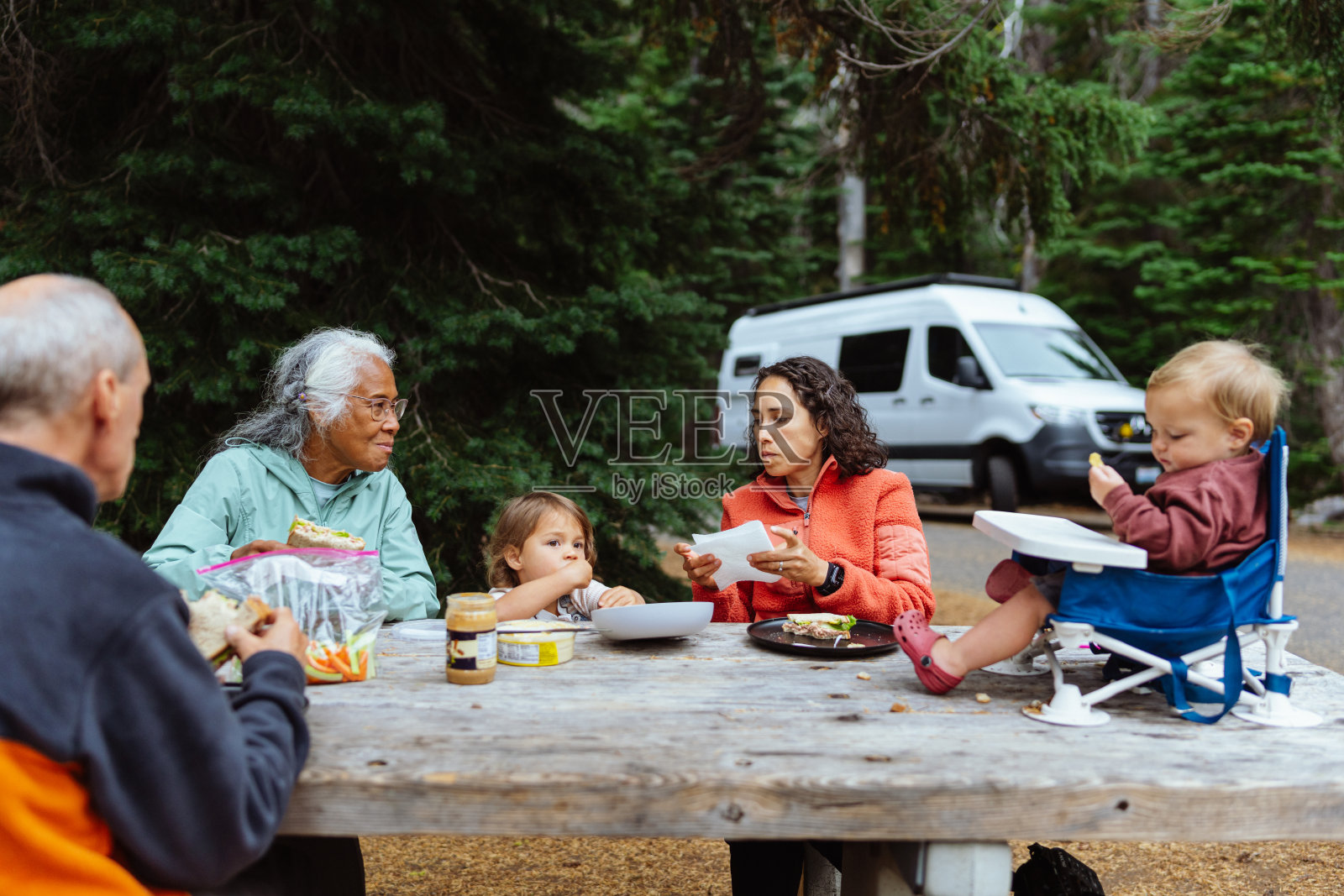 几代同堂的家庭在野炊桌上一起吃饭照片摄影图片