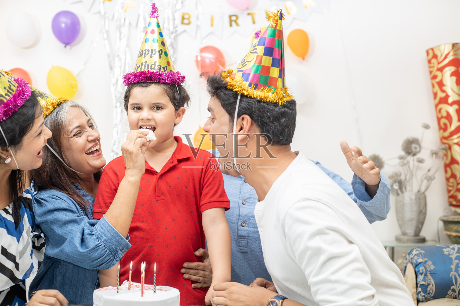 快乐的印度亚洲多代家庭庆祝孩子的生日派对。孩子吃蛋糕照片摄影图片