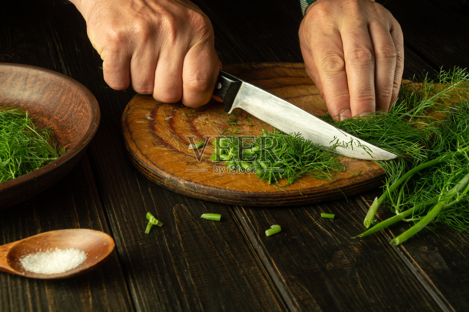 在准备国菜或素菜之前，厨师用手在厨房的砧板上切新鲜的鸡毛。茴香的供应或罐装照片摄影图片