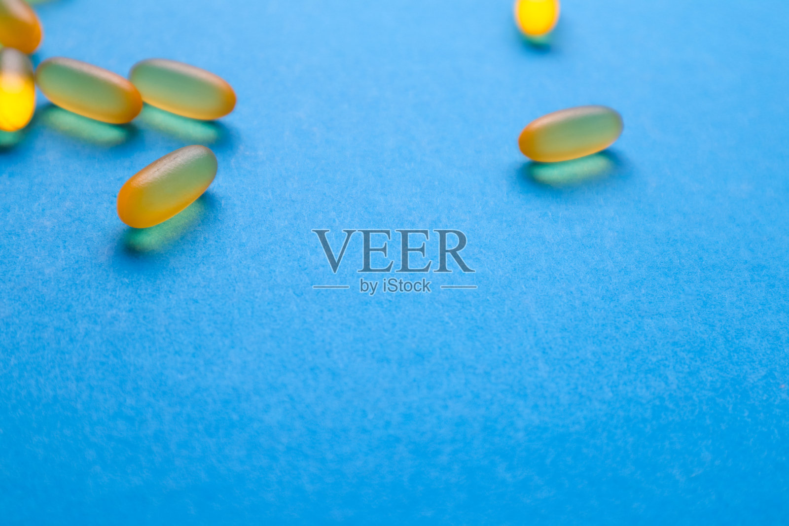 鱼油胶囊，欧米茄3，维生素e在蓝色背景与复制空间。保健、维生素、补品每日摄入的概念。照片摄影图片