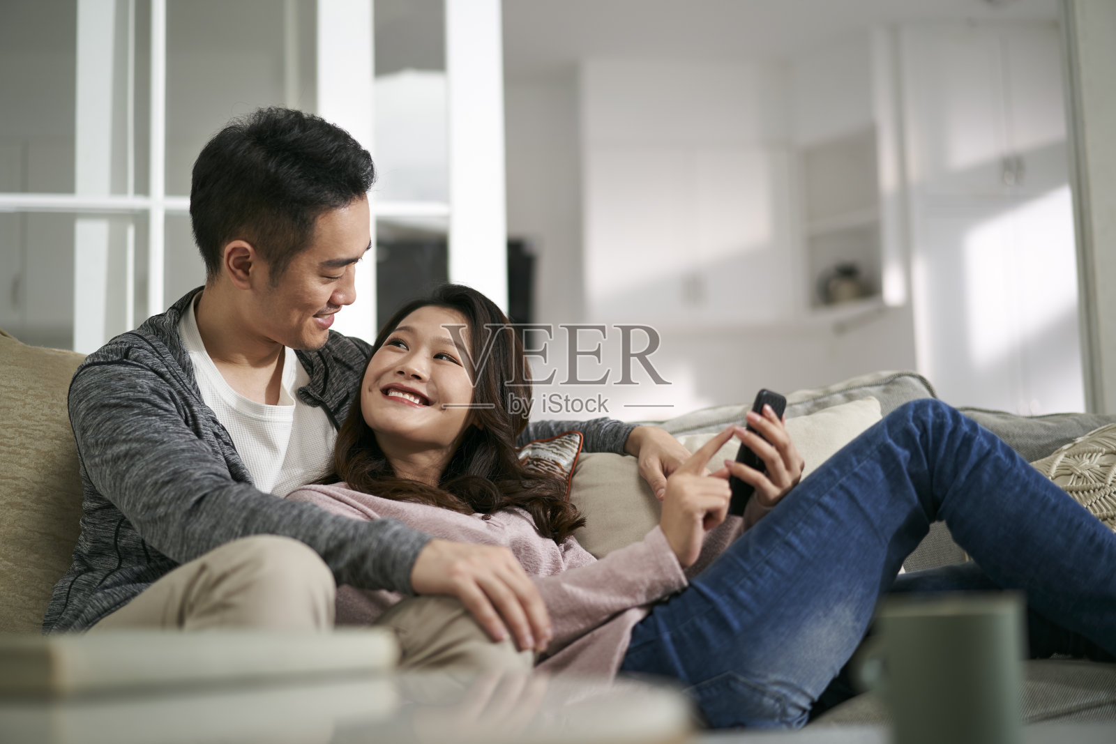 幸福的年轻亚洲夫妇在家里一起看手机照片照片摄影图片