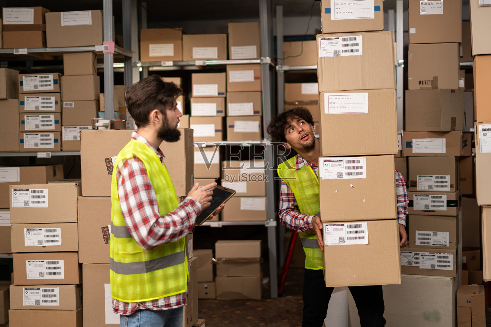 两名仓库混血工人正在使用数字平板电脑记录库存和准备发货。物流员工使用仓库管理软件进行大型配送。照片摄影图片