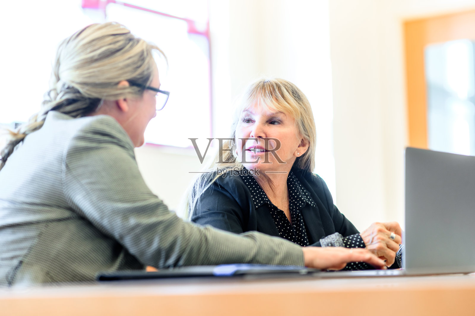 女性在现代办公室里用笔记本电脑一起工作，财务顾问和高级女性照片摄影图片