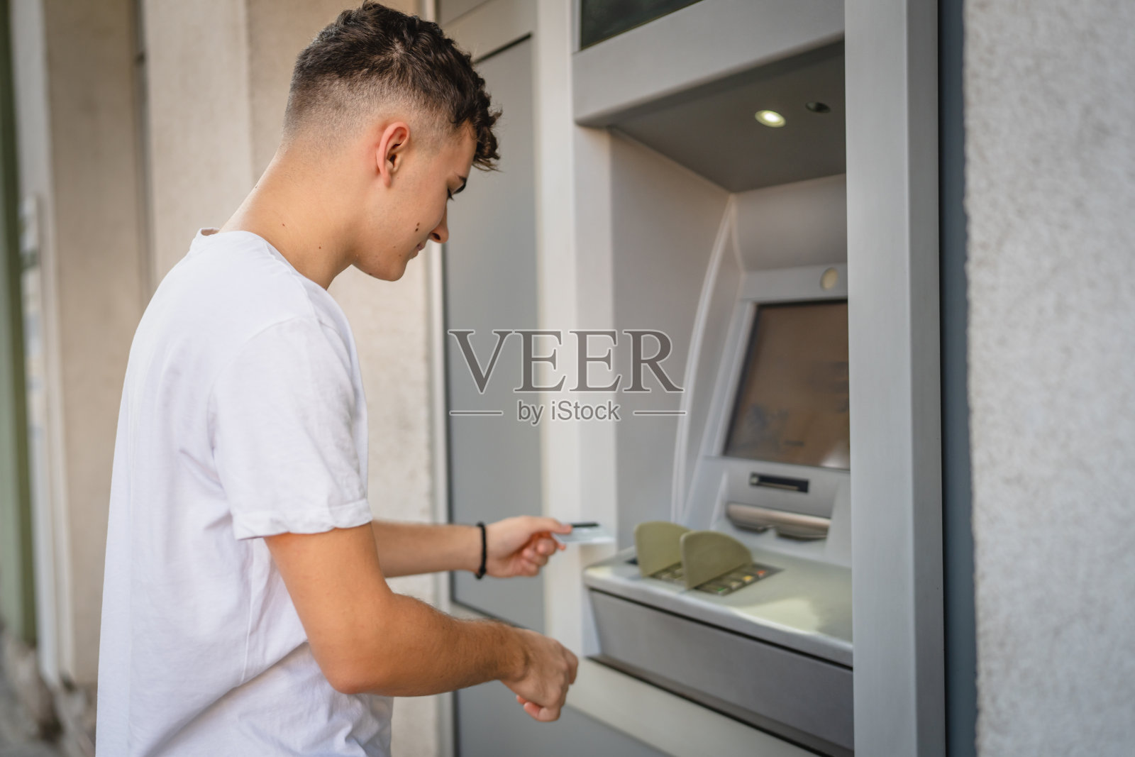 一名青少年学生用信用卡在自动取款机取钱照片摄影图片