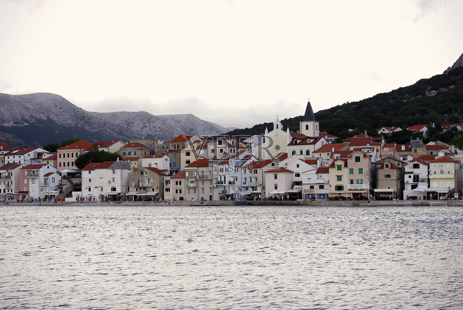 欧洲克罗地亚克尔克岛上的热门旅游目的地巴斯卡村的城市景观图像。傍晚，亚得里亚海的一个港口，背景是群山。照片摄影图片