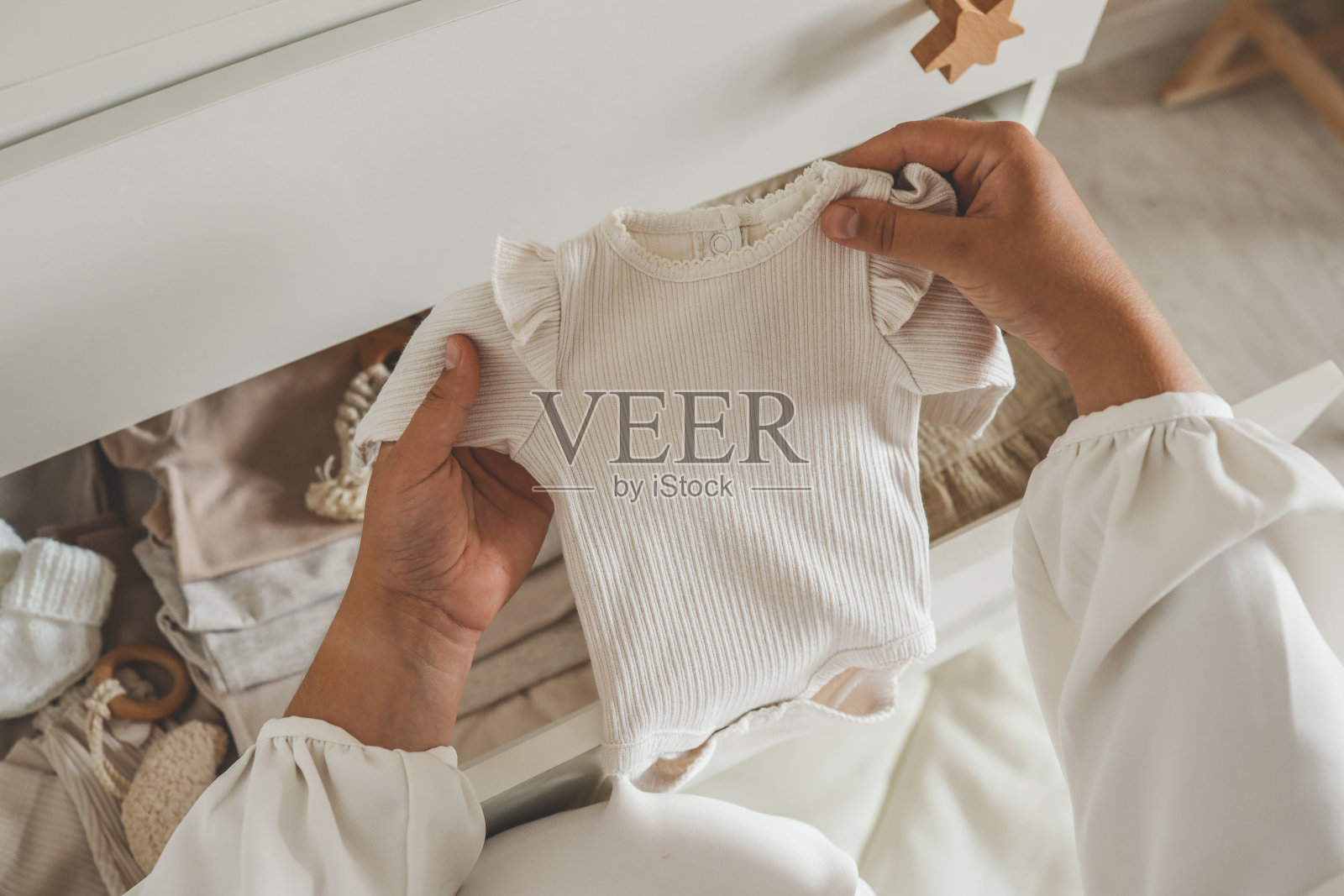 一位孕妇手里拿着一件米色的紧身衣，这是怀孕的概念照片摄影图片