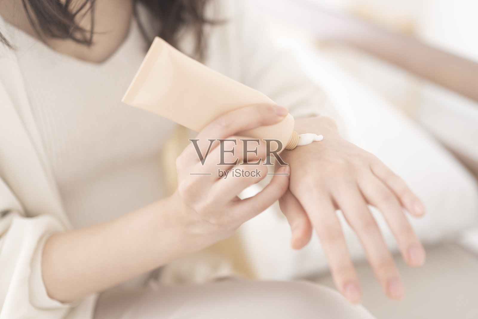 一位亚洲妇女正在给手上涂护手霜。照片摄影图片