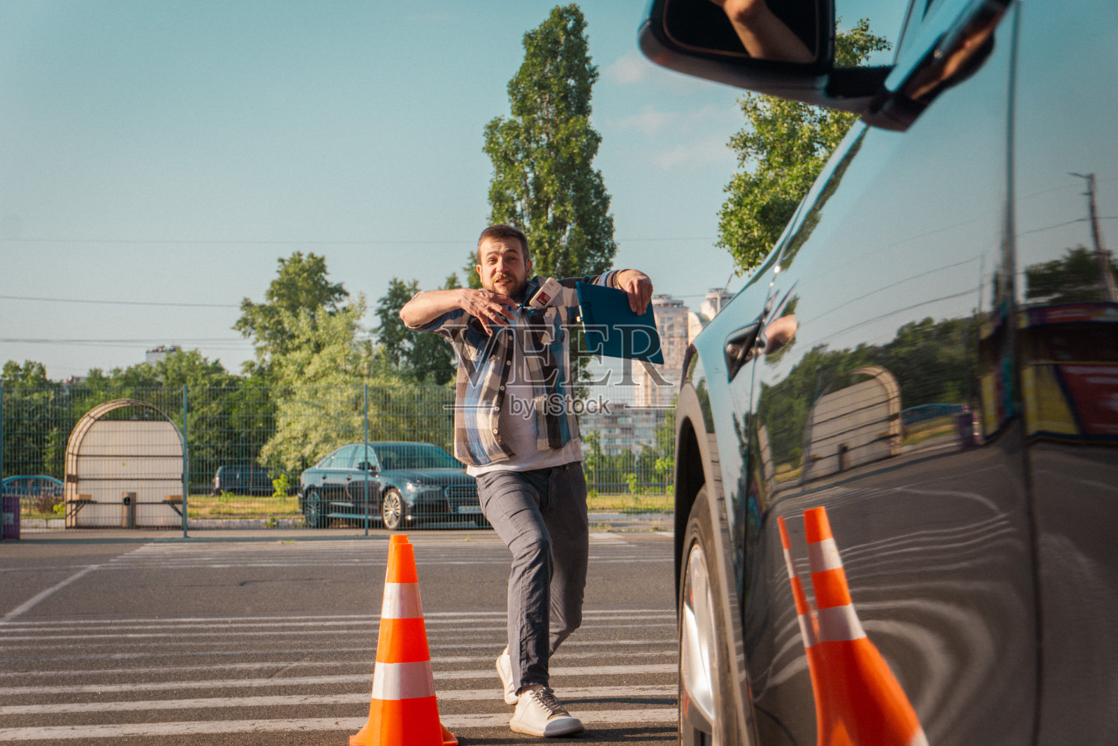 驾驶教练在训练如何停车时用手做手势。汽车附近的交通锥。驾驶考试，驾驶课程，考试概念照片摄影图片