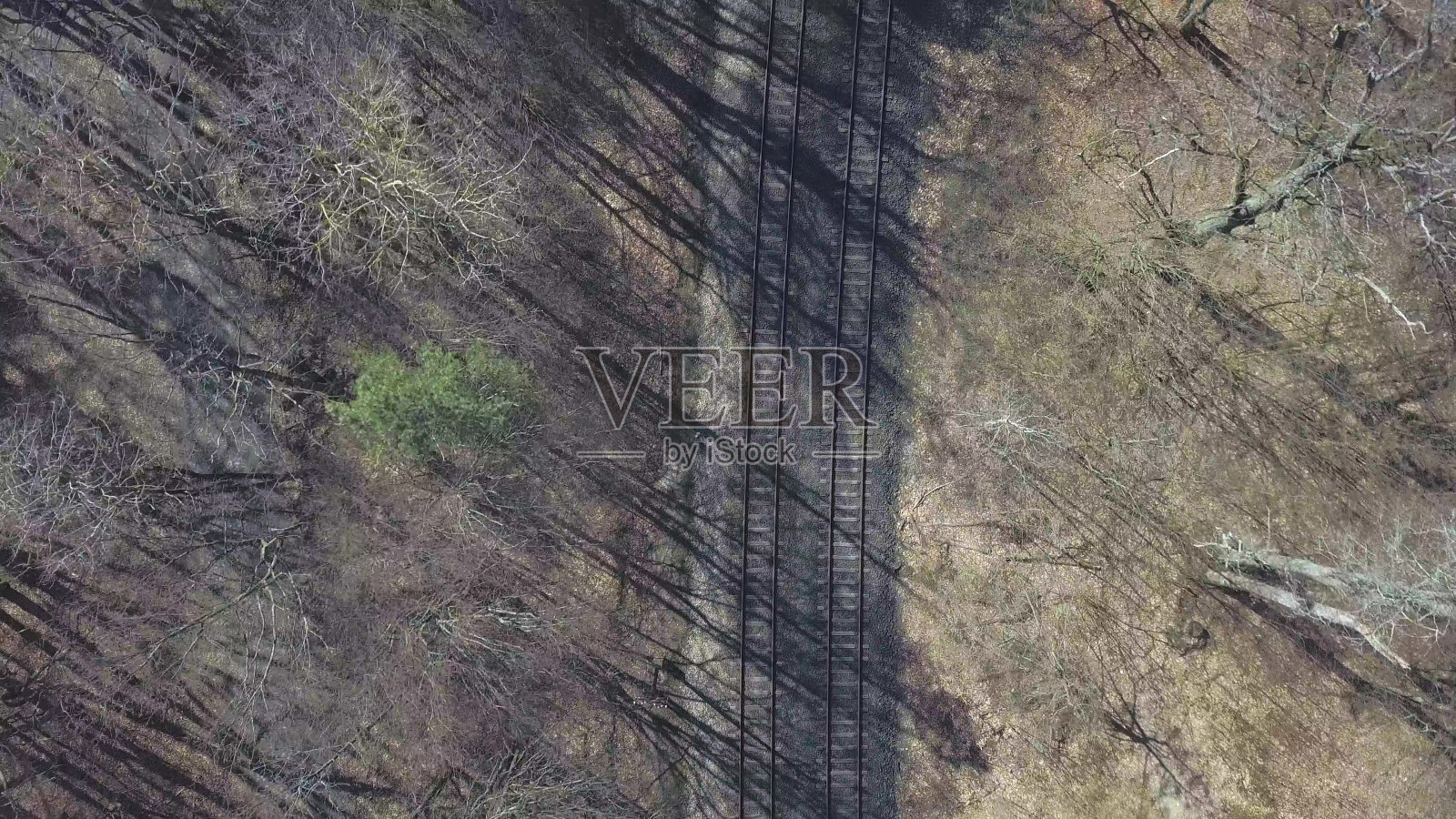 空中无人机在阳光明媚的日子里飞过树林里的铁轨照片摄影图片