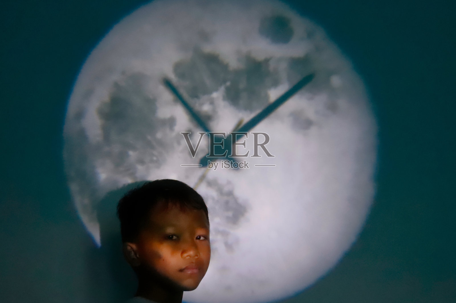 一个亚洲男孩，穿着一件带有时钟背景的白衬衫照片摄影图片