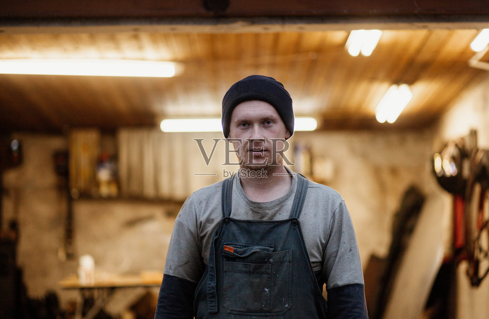 穿着工作服的男技师在车库车间的背景下照片摄影图片