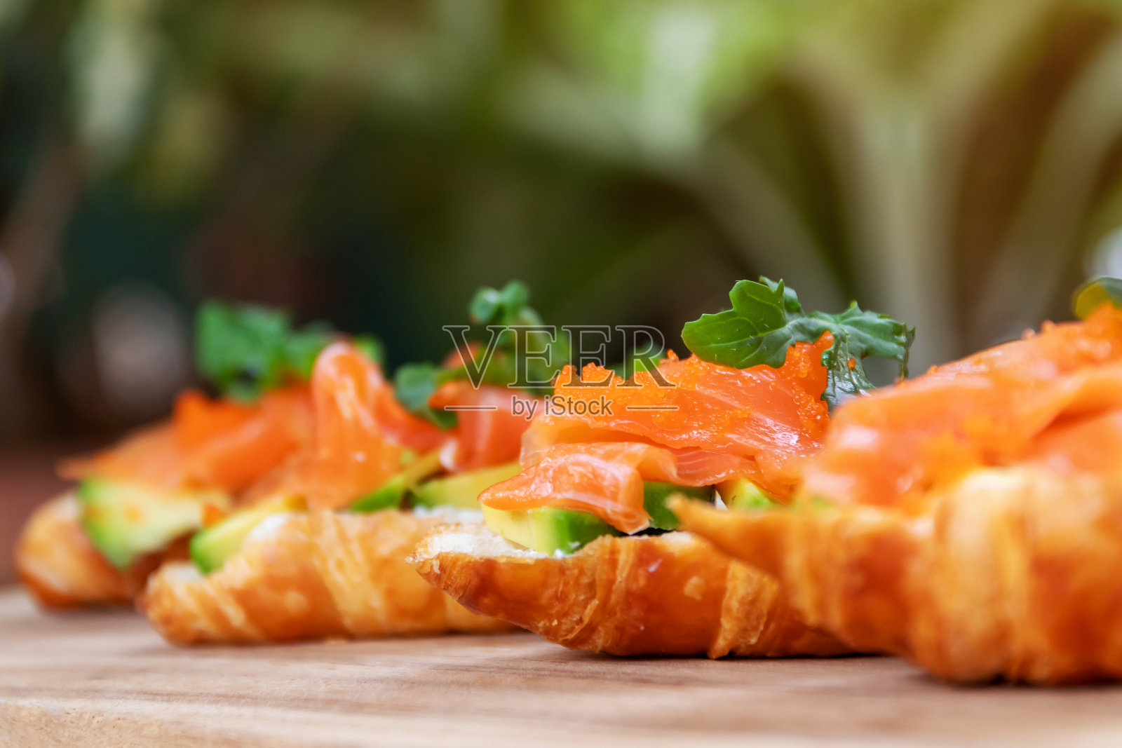 烟熏三文鱼配奶油芝士和牛油果，配新鲜牛角面包。照片摄影图片