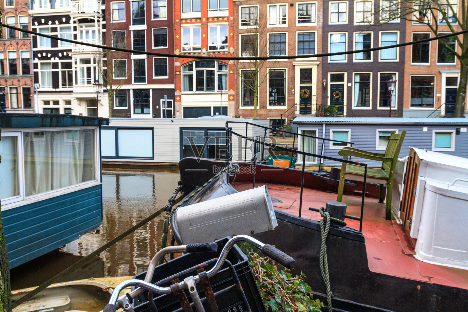 在一个阳光明媚的冬日的城市景观-在阿姆斯特丹历史中心的水渠上的船屋照片摄影图片