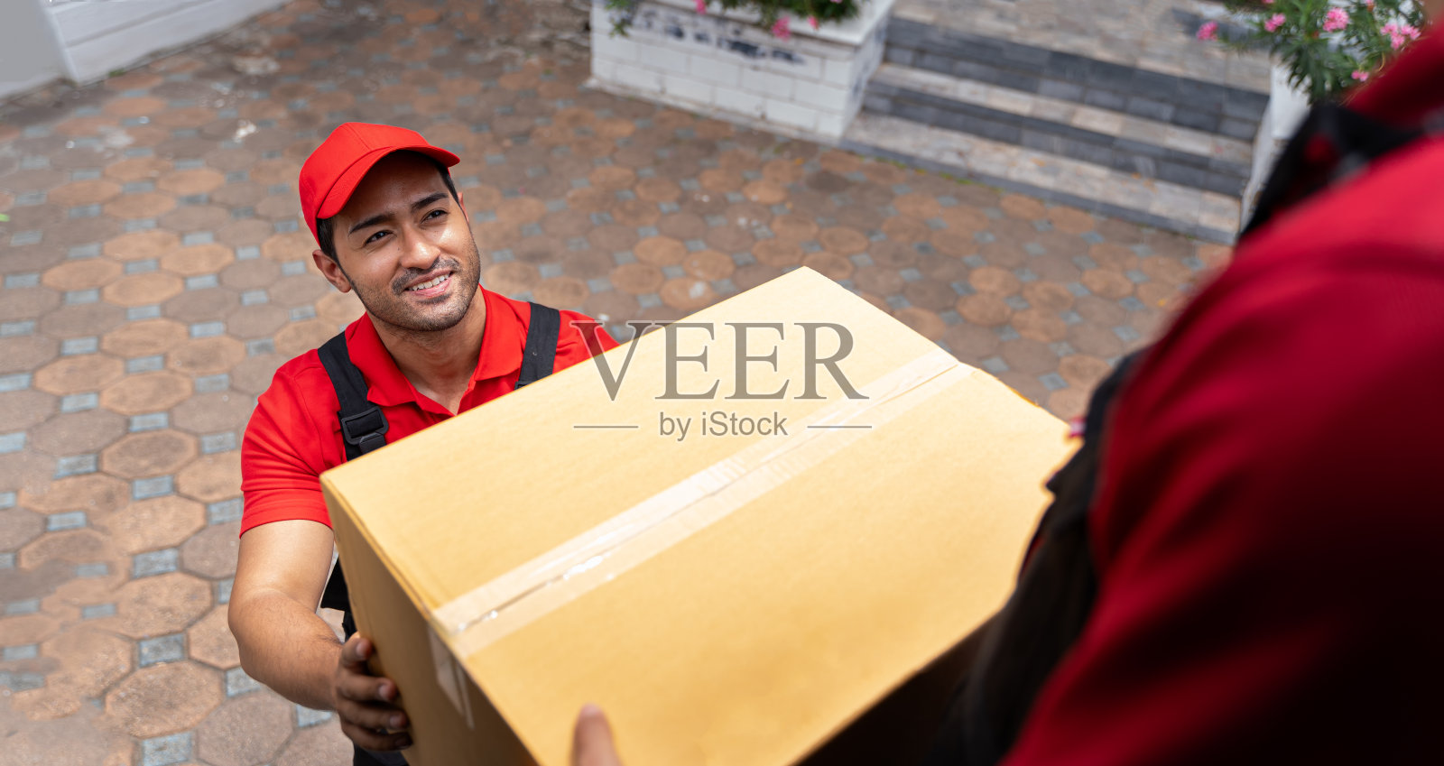一名快递员穿着航运公司的制服。从装满包裹的卡车后面的团队那里接收或搬运一箱货物。在交付过程中向客户提供运输理念。照片摄影图片