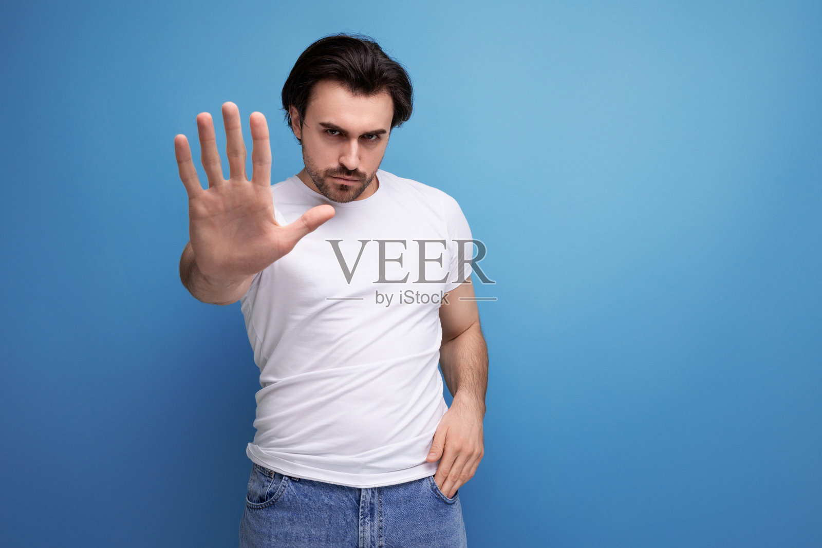 身穿白色t恤的黑发野蛮年轻人表示不同意照片摄影图片