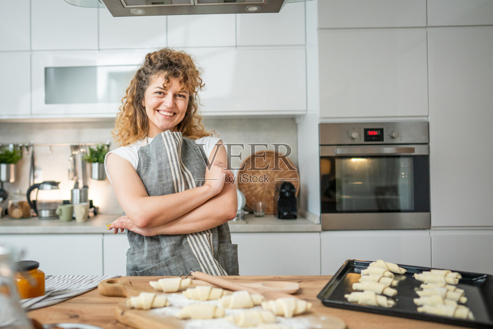 一个快乐的年轻白人妇女穿着围裙在厨房微笑照片摄影图片