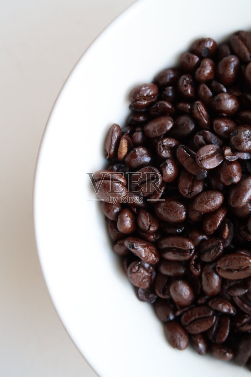 在一个白色的碗里，黑色的烤过的油腻的咖啡豆的特写图像照片摄影图片