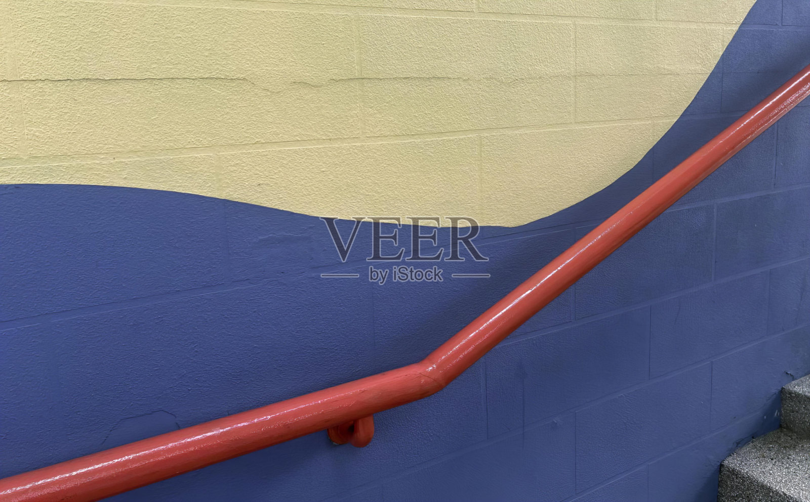 一张蓝色墙上的红色扶手的照片，有栏杆的台阶通向蓝色和黄色的墙。照片摄影图片