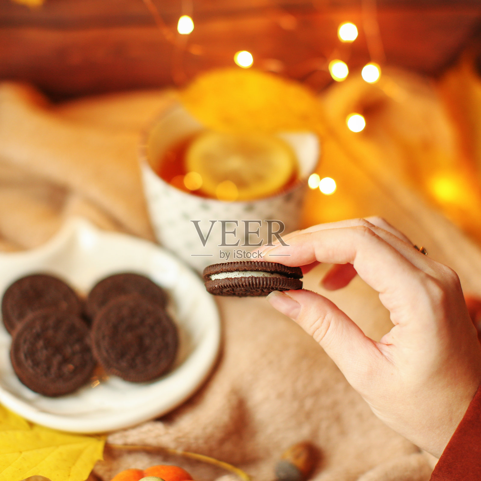 木桌上有饼干、南瓜、秋叶和针织毛衣的茶杯。秋天的概念。俯视图，平铺。照片摄影图片