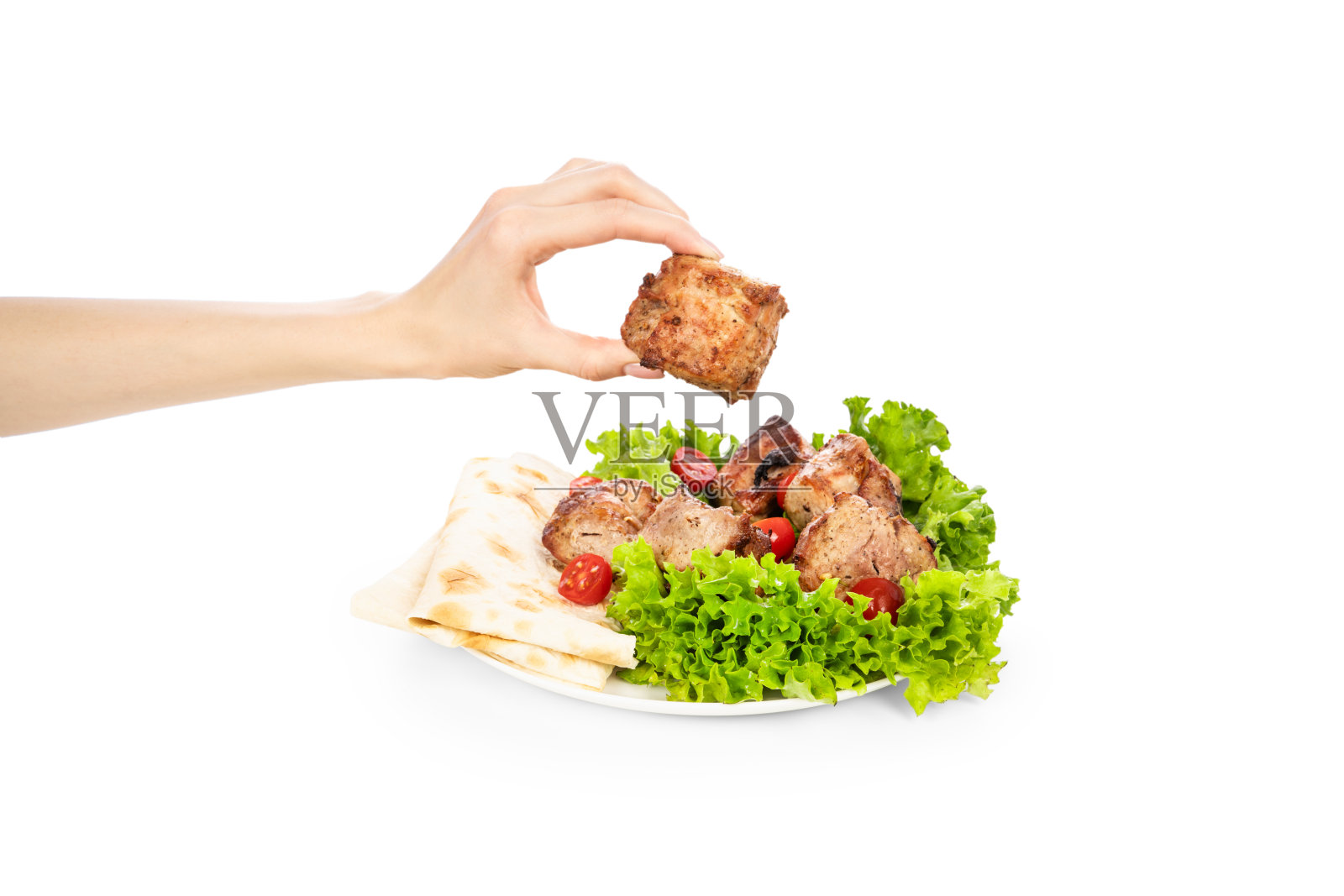 美味的烤肉和蔬菜放在白色盘子上，孤立在白色背景上。女人手里拿着肉照片摄影图片