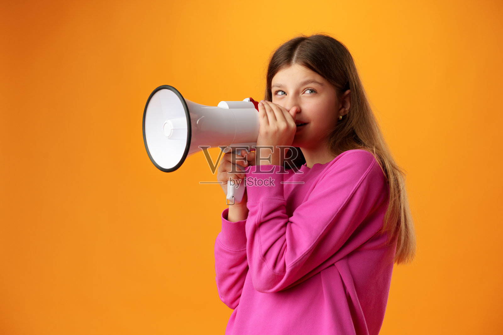 十几岁的女孩用黄色背景的扩音器宣布照片摄影图片