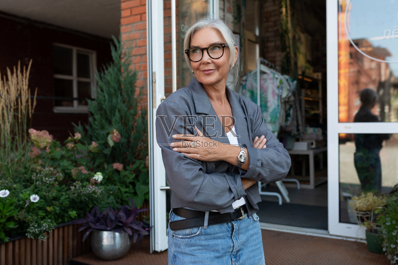 一位成功自信的中年女性，穿着一件灰色时尚夹克，出现在都市环境中照片摄影图片