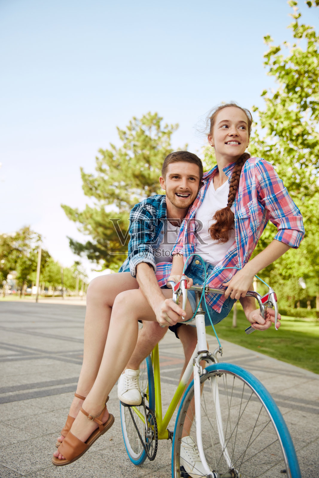 一起冒险。一对情侣在城市街道上骑自行车的垂直肖像。可爱的骑手们玩得很开心。浪漫的关系。照片摄影图片