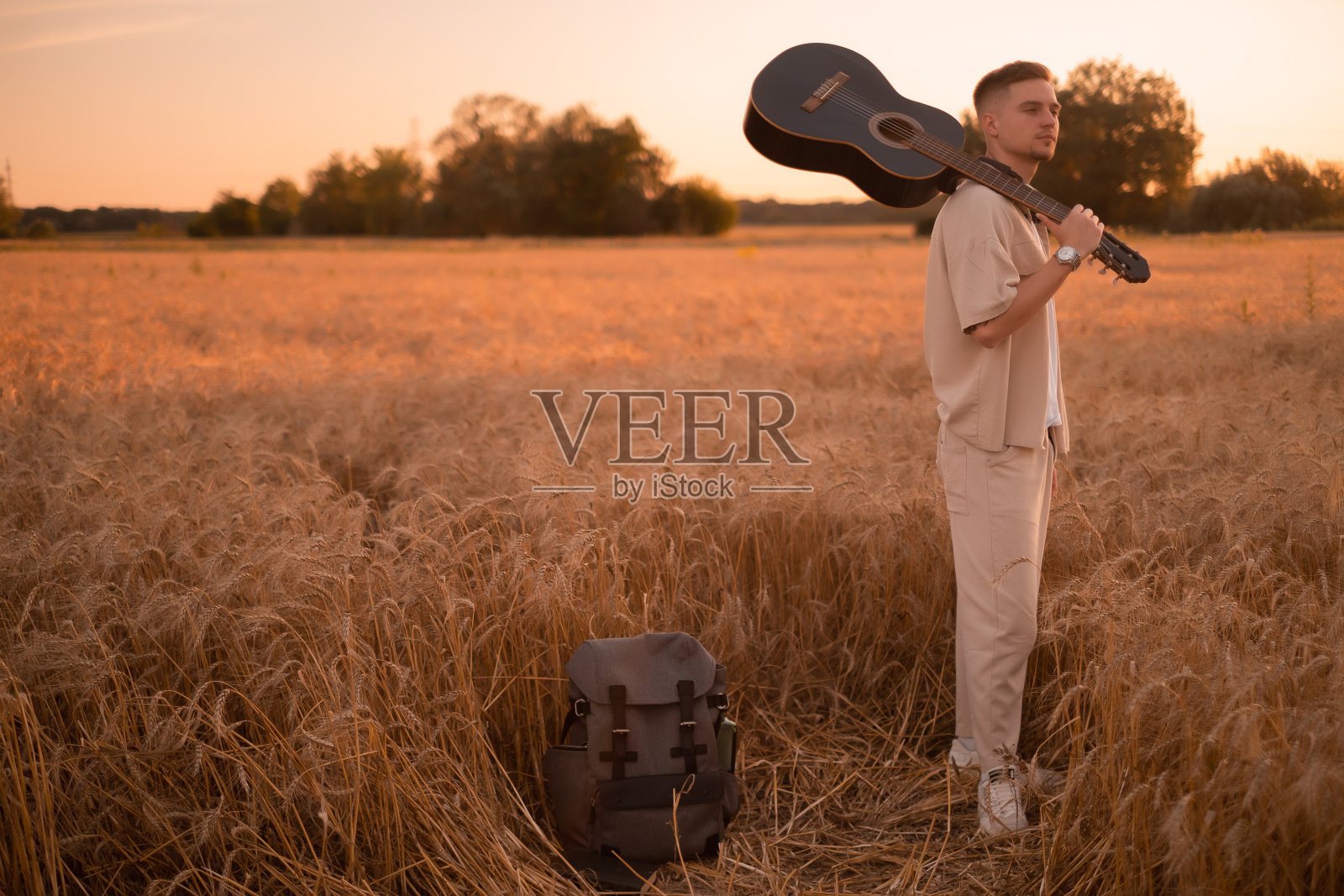 营地里一个拿着吉他的男人。炉火边的歌。乡村原声吉他手，音乐歌曲。穿着衬衫拿着吉他的性感男人。潮人时尚照片摄影图片