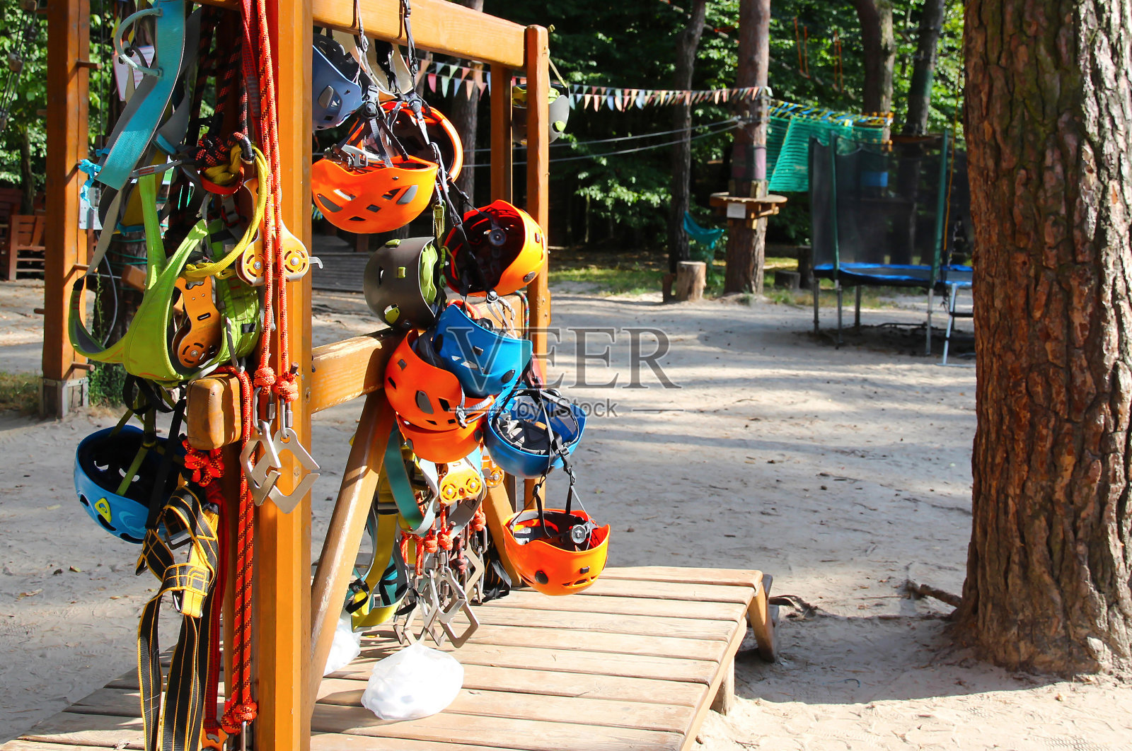 攀爬装备——挂在绳索公园板上的彩色头盔。照片摄影图片