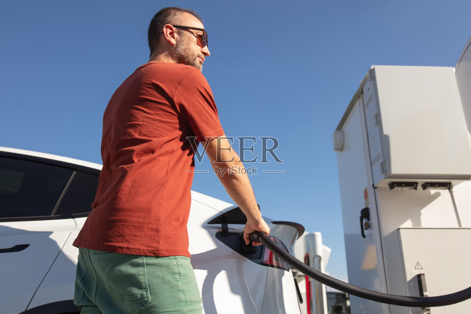 男子在公共充电器上给电动车充电。照片摄影图片