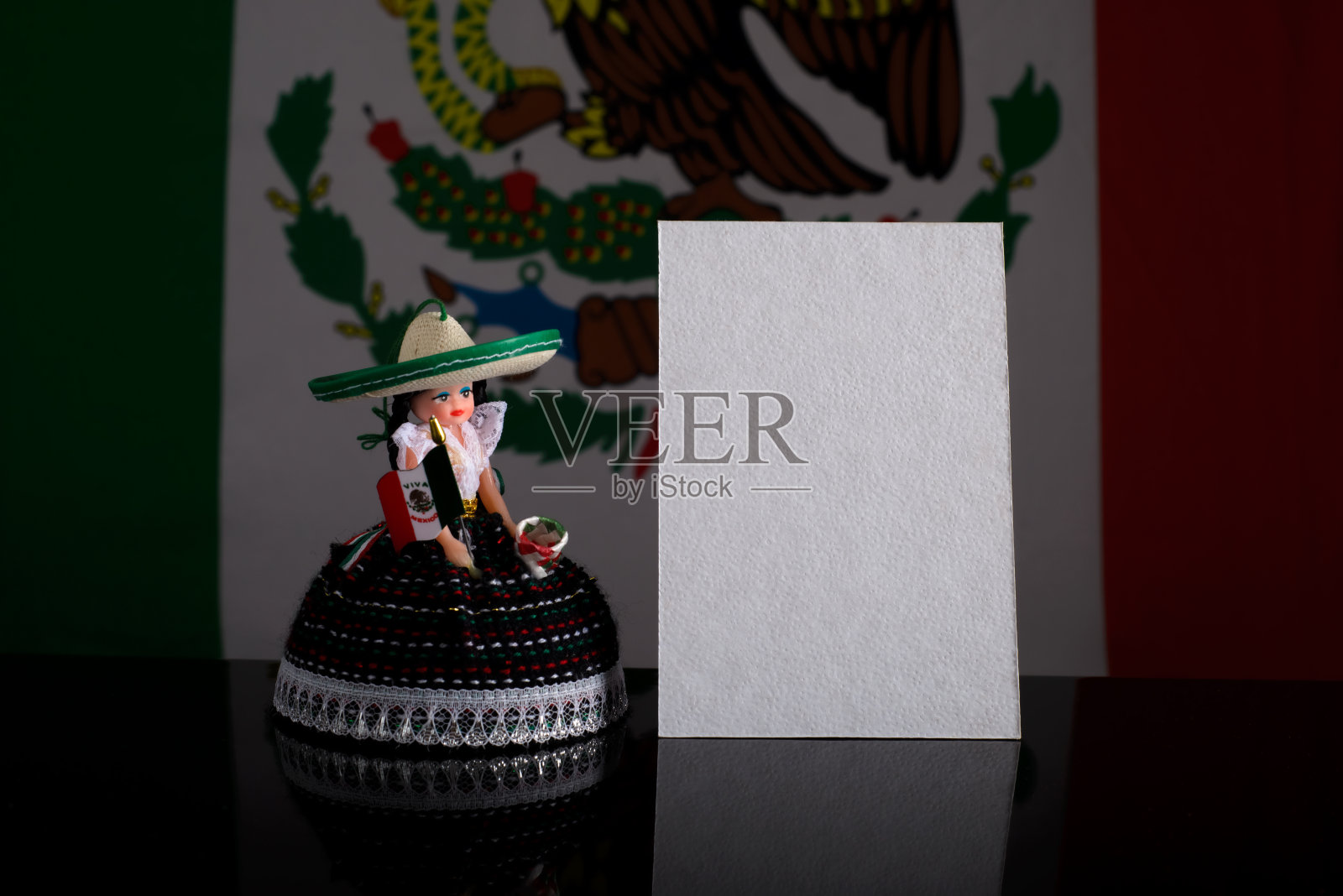 小娃娃与墨西哥妇女的数字旁边的空白卡片与墨西哥国旗的背景。墨西哥庆祝活动的模型。照片摄影图片